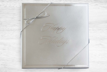 silver happy holidays box shown on a white wood background